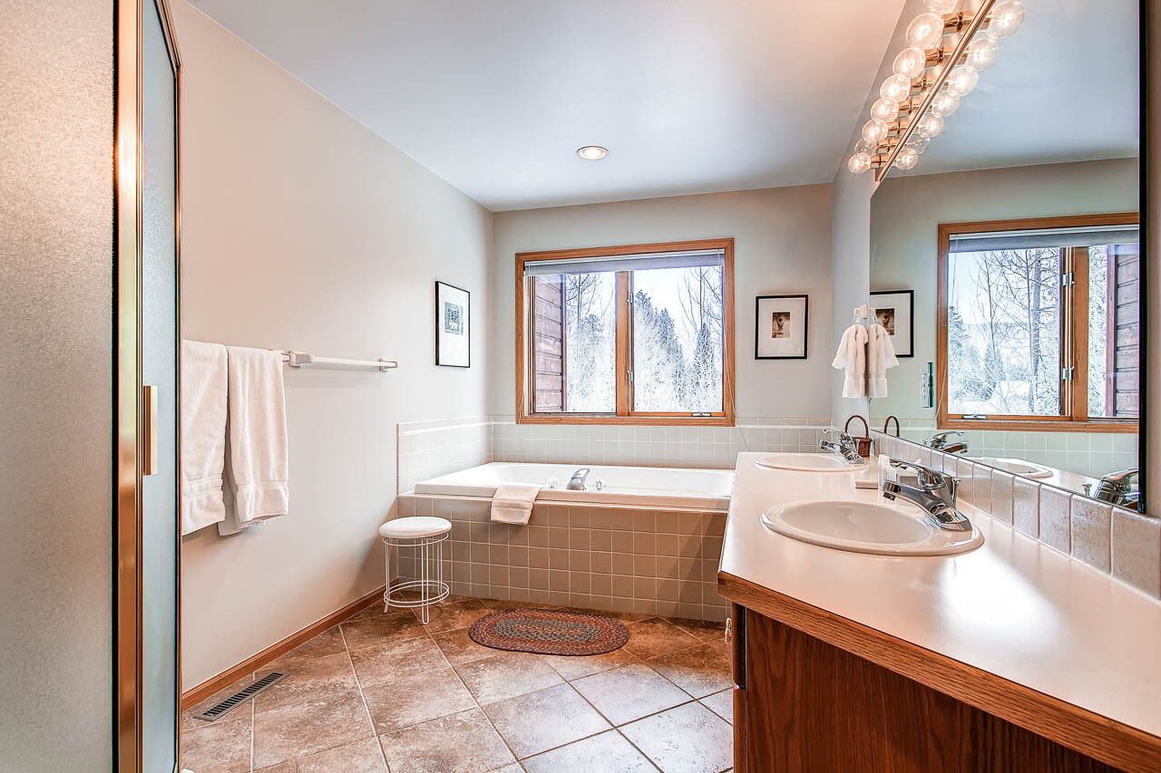 Une salle de bain moderne avec une baignoire sur pieds, deux vasques et de grandes fenêtres.