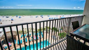 A balcony with a view of a beach and a swimming pool.
