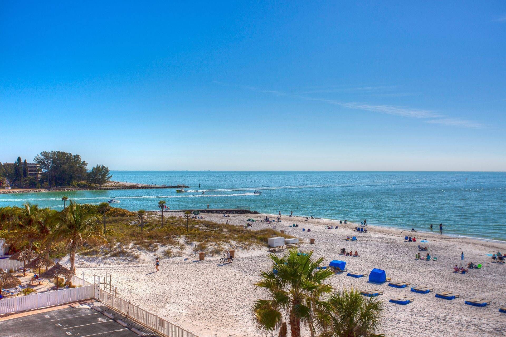 Een strand met wit zand, palmbomen en een helderblauwe lucht.
