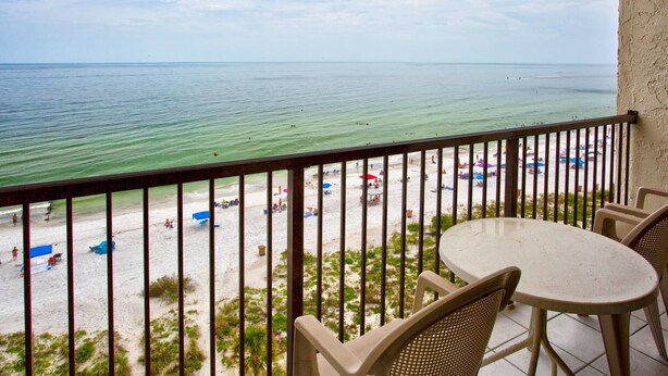 A balcony with a view of a beach, a table, and chairs. - Amazing 9th Floor Beachfront View From Private Balcony. Pool/HotTub, Beach, + Tickets to Fun Daily! (Madeira Beach)