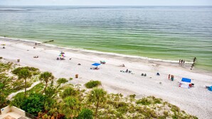 A beach with clear water, people sunbathing, and umbrellas. - Amazing 9th Floor Beachfront View From Private Balcony. Pool/HotTub, Beach, + Tickets to Fun Daily! (Madeira Beach)