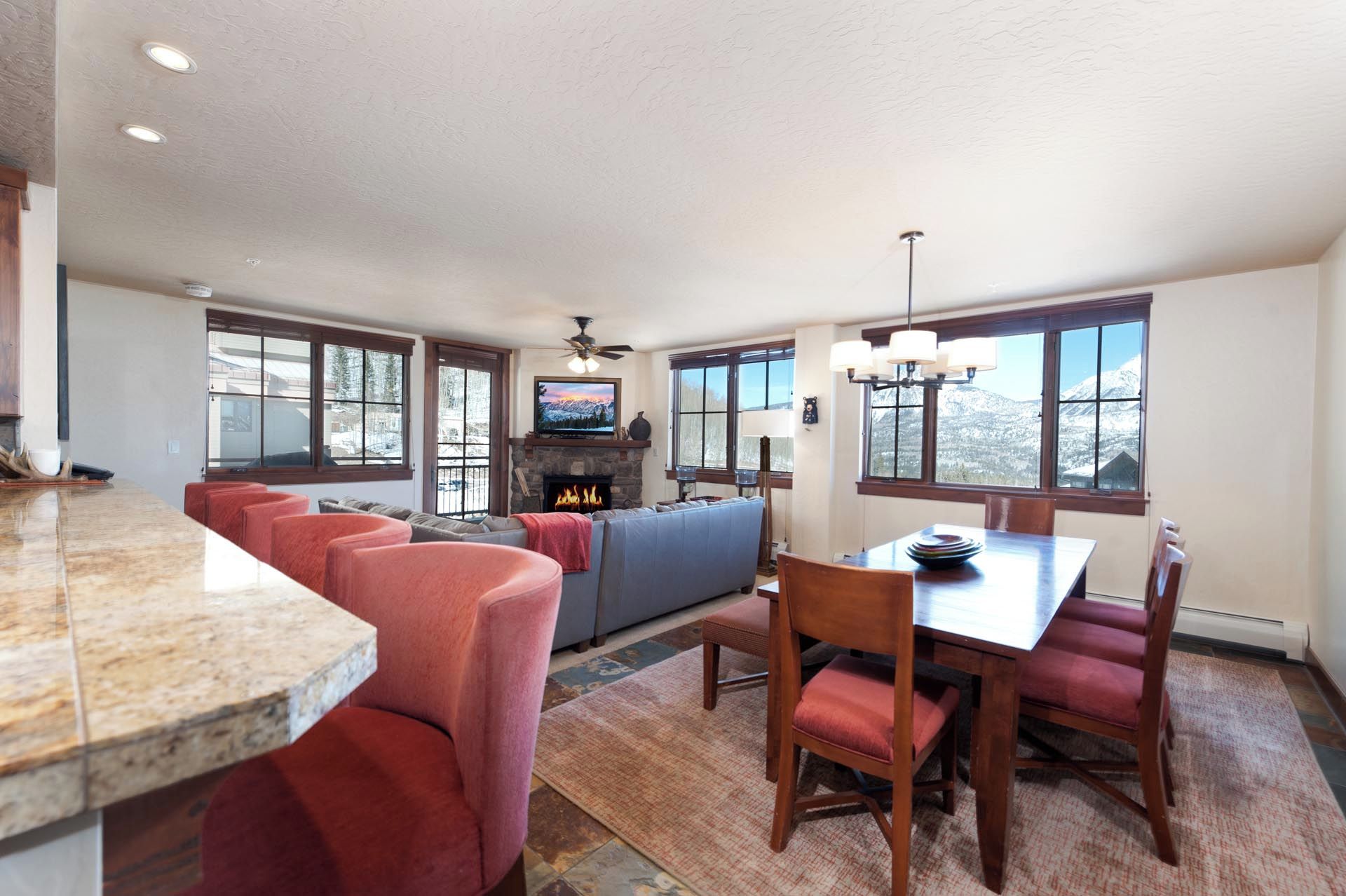 A spacious living area with a stone fireplace, a large TV, and a dining table with chairs.