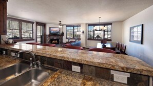 A spacious kitchen with granite countertops, a built-in sink, and large windows offering mountain views. - Premier Building at Purgatory - Views - Ski in/Ski Out - Corner Unit (Durango)