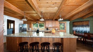 Un'ampia cucina con una grande isola, travi in legno a soffitto e vista sull'esterno.
