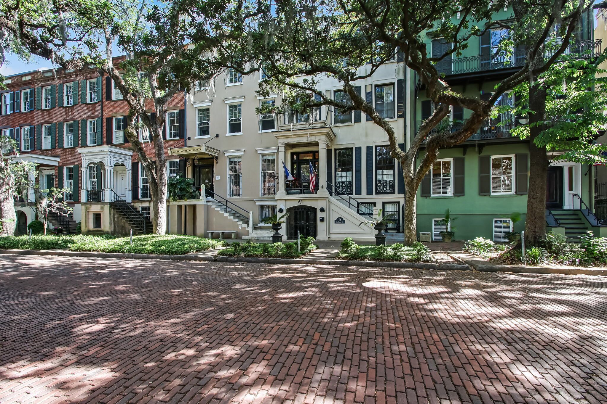 A row of historic brick townhouses with a central building featuring a grand entrance and a staircase.
