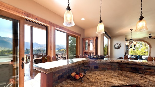 A spacious kitchen with a large island, wooden cabinetry, and a view of mountains through large windows.