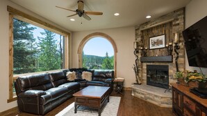 A living room with a leather sectional sofa, a wooden coffee table, a fireplace, and a stone fireplace surround.