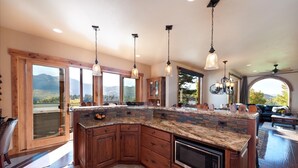 A spacious kitchen with a large island, wooden cabinets, and a built-in microwave.