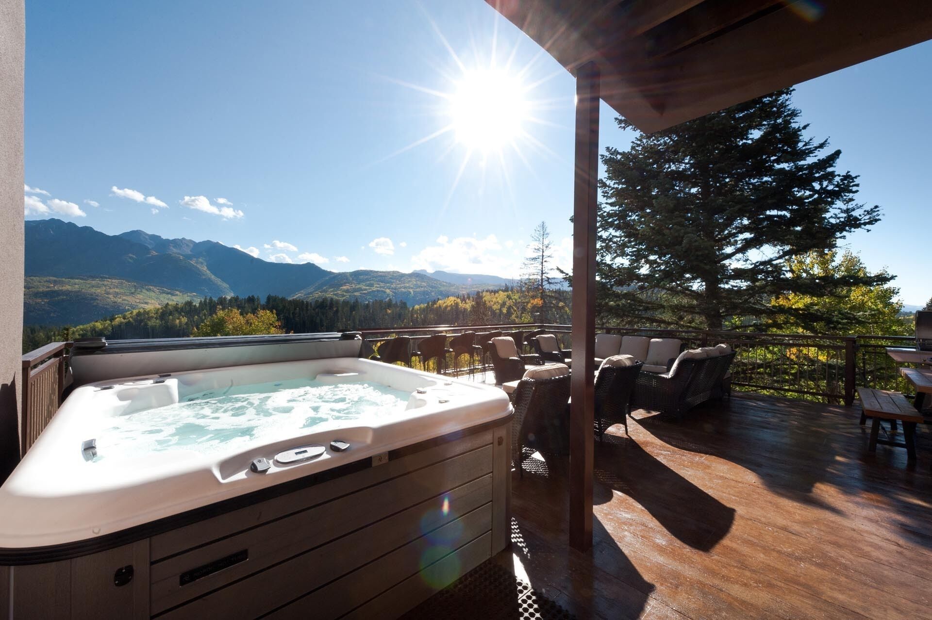 Een hottub op een houten terras met uitzicht op de bergen.
