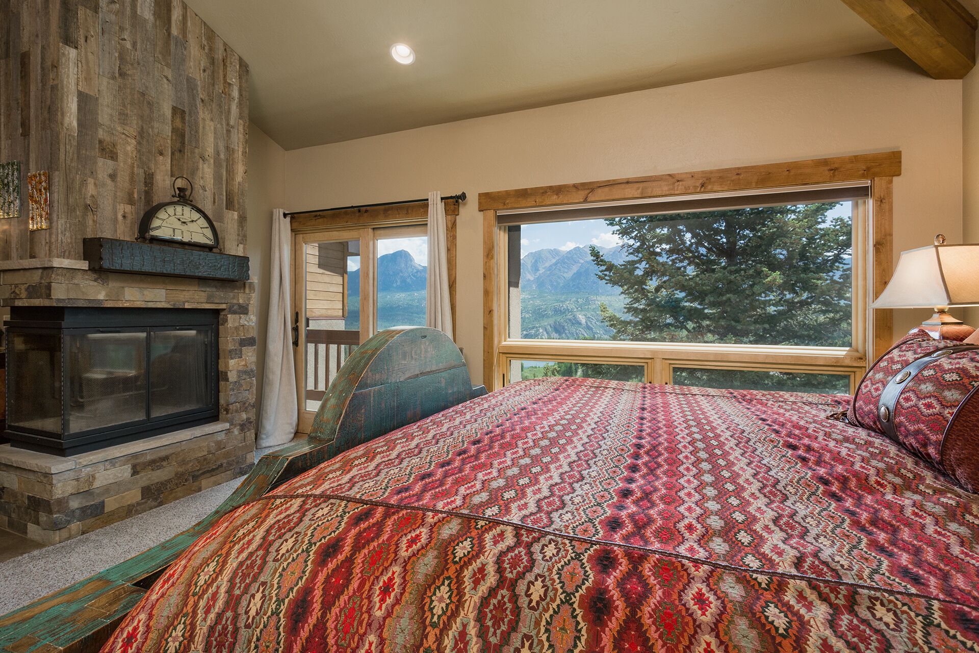 Quarto com cama grande, lareira e janela com vista para a montanha.