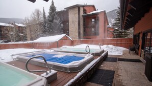 Ein Whirlpoolbereich mit drei Badewannen, einer Steinwand und einer Holzterrasse.