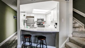 Eine moderne Küche mit Kochinsel, Barhocker und Mikrowelle.