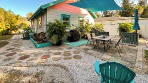 Une maison dotée d’un patio comprenant une table et des chaises, entouré de plantes en pot et d’une clôture décorative.