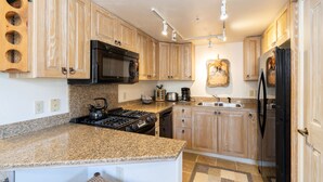 A kitchen with wooden cabinets, granite countertops, a stove, microwave, refrigerator, and a coffee maker. - DOUBLE DIAMOND 3- Condo with Loft, Telluride near Chair 7 and Shuttle Route (Telluride)