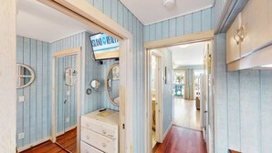Un pasillo con paneles de madera azul, un tocador de estilo antiguo con espejo, y un cartel que dice 'ISLAND REALTY'.
