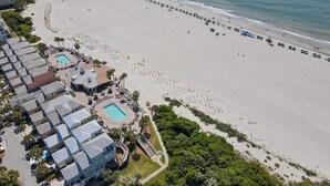 An aerial view of a resort with multiple buildings, a beach, and a pool area.
