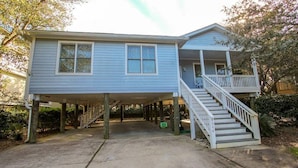 A two-story house with a covered porch and a staircase leading to the upper level. - Spacious home just a short walk to the beach with a screen porch (Isle of Palms)