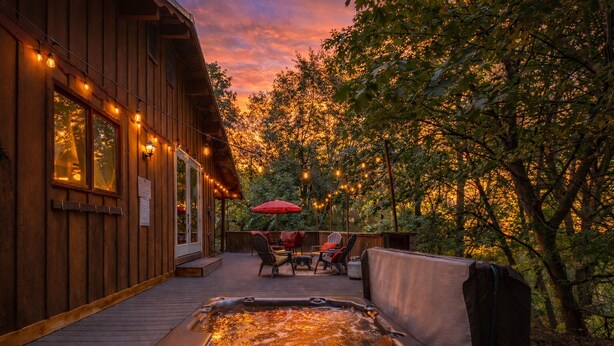 Eine Holzterrasse mit Whirlpool, Sitzgelegenheiten im Freien und Lichterketten.