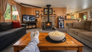 Ein gemütliches Wohnzimmer mit Kamin, Fernseher und einer Schüssel Popcorn auf einem Couchtisch.