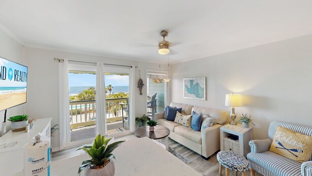Ein Wohnzimmer mit Fernseher, einer Couch, einem Couchtisch und Blick auf den Strand.