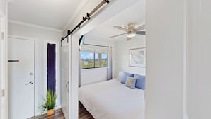 Ein Schlafzimmer mit Bett, Deckenventilator, Fenster mit Aussicht und Tür mit einem Rauchverbot-Schild.