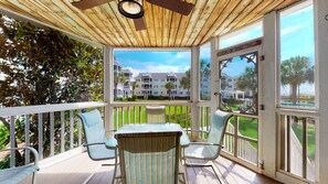 A covered outdoor area with a table and chairs, a ceiling fan, and a view of a multi-story building with balconies. - Wild Dunes updated condo-Screened porch, community pool & beach path, golf! (Isle of Palms)