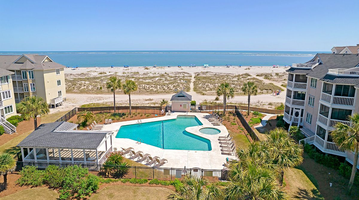 Un espace piscine avec vue sur la plage, entouré d’immeubles.