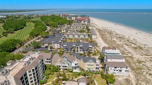 A coastal resort with multiple-story buildings, a golf course, and a beach.