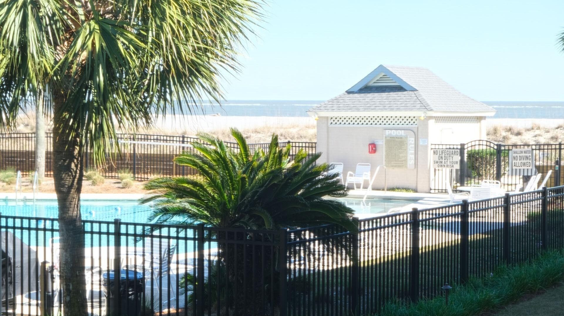 Un espace piscine doté d’un poste de surveillance pour sauveteur, d’une piscine clôturée et offrant une vue sur la plage.