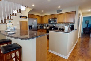 A modern kitchen with wooden cabinets, stainless steel appliances, and a granite countertop.
