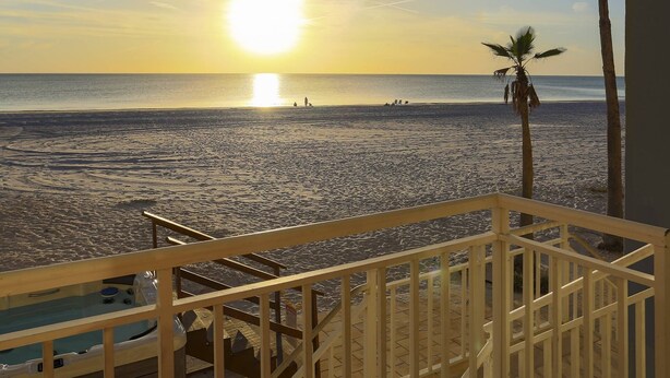 Ein Balkon mit Blick auf Strand und Meer bei Sonnenuntergang.