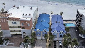 Ein Strandhotel mit mehreren Gebäuden, einem Schwimmbad und einem Strand im Hintergrund.
