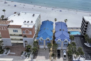 A beachfront hotel with multiple buildings, a swimming pool, and a beach in the background.