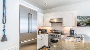 A modern kitchen with white cabinets, stainless steel appliances, and a granite countertop.