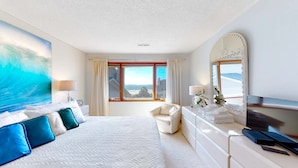 Habitación de hotel con una cama grande, zona de estar, un ventanal con vistas y un televisor de pantalla plana.