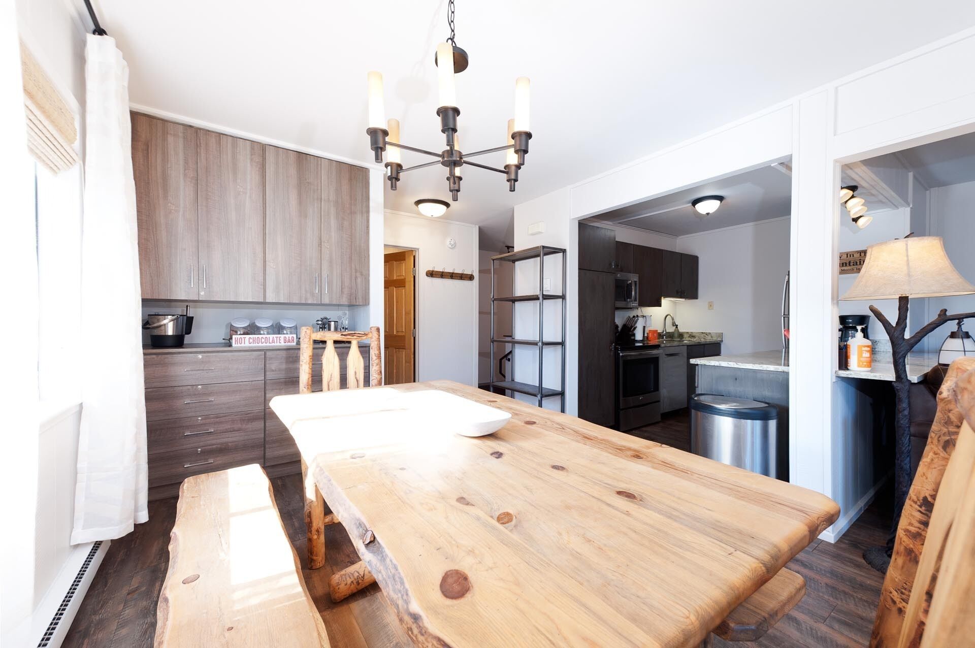 A modern kitchen with wooden cabinets, a central island, and a chandelier.