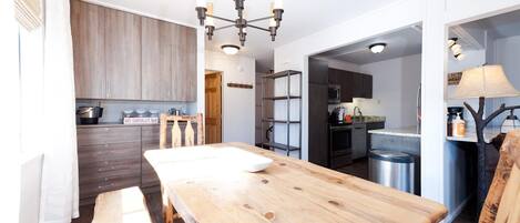A modern kitchen with wooden cabinets, a central island, and a chandelier.