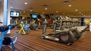 A gym with multiple treadmills and elliptical machines, a television screen, and a carpeted floor. - Affordable Purgatory Ski in/Ski Out Condo in the Main Plaza (Durango)