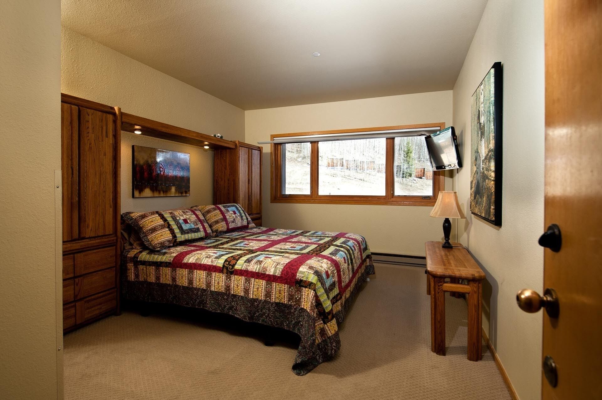 Une chambre avec un grand lit, une fenêtre, une télévision et une porte.