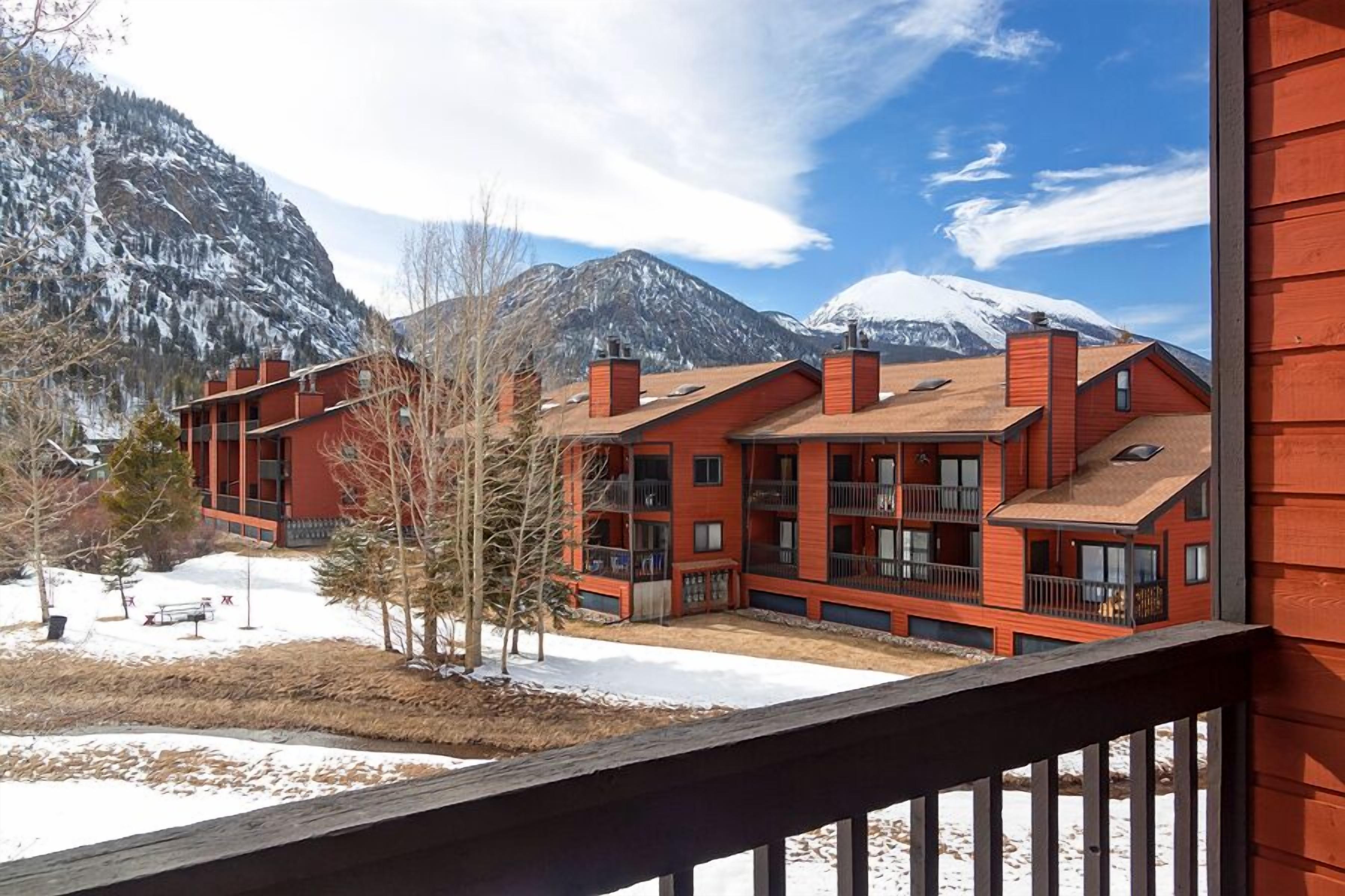 A red building with multiple balconies and a view of snow-capped mountains.