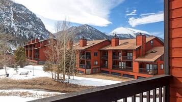 A red building with multiple balconies and a view of snow-capped mountains.