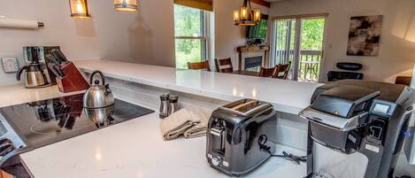 A modern kitchen with a central island, a kettle, a toaster, and a coffee maker.