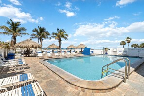 A pool area with lounge chairs and palm trees.