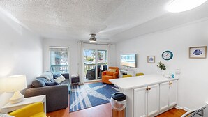 A modern living room with a sofa, a dining table, and a kitchen area. - Nestled Just Steps Away from the Sun-Kissed Shores! (Isle of Palms)