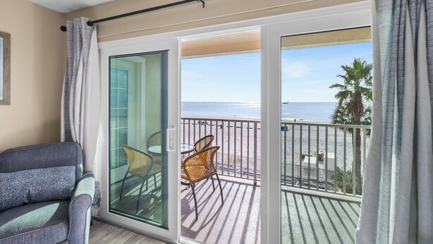 A balcony with a view of the beach, a chair, and a sofa. - Beach Front Corner Unit - Beach Place #212 (Madeira Beach)