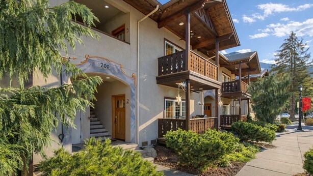 A multi-story building with a wooden balcony, a staircase leading to the entrance, and a clear sky. - Downtown Luxury | Walk to It All | Garage | BBQ (Leavenwort)