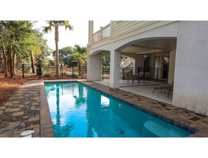 A swimming pool with a tiled edge, surrounded by a brick pathway. - Beautiful beach home with wrapping porches, private pool, and ocean view peek (Isle of Palms)
