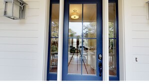 A blue door with a glass panel and a light fixture above it. - Beautiful beach home with wrapping porches, private pool, and ocean view peek (Isle of Palms)