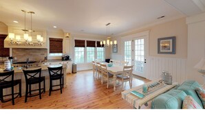 A spacious kitchen with a dining area, wooden floors, and a cozy seating area with a sofa and chairs. - Beautiful beach home with wrapping porches, private pool, and ocean view peek (Isle of Palms)