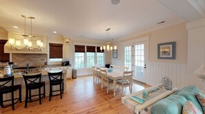 A spacious kitchen with a dining area, wooden floors, and a cozy seating area with a sofa and chairs.